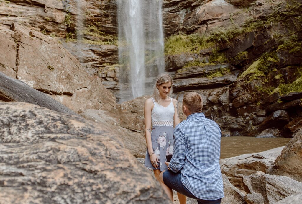Man proposing to woman in front of Toccoa Falls waterfall in Georgia.