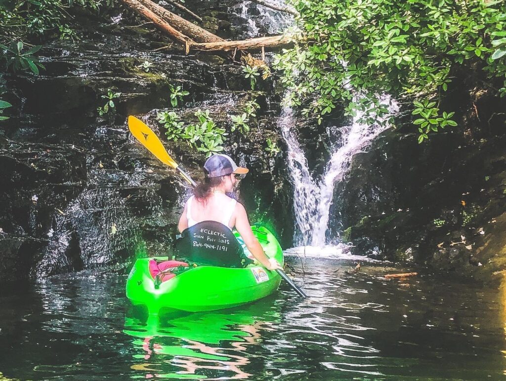 Woman in kayak in front of waterfall on Lake Jocassee in South Carolina.