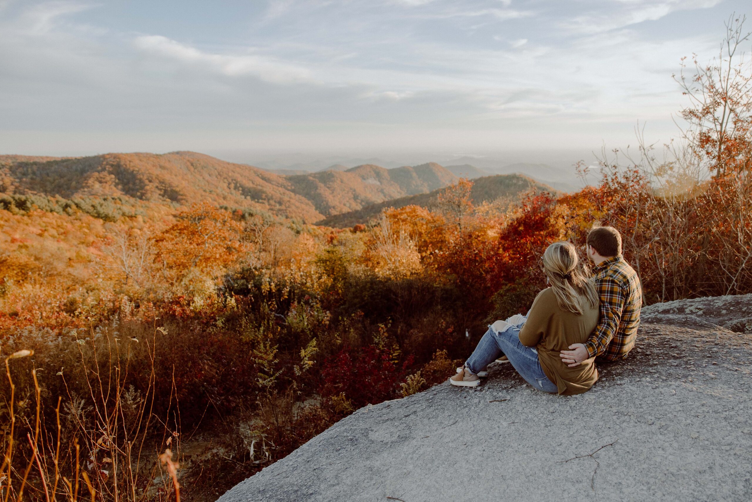 Couple sitting on rock at Sassafras Mountain in South Carolina during fall.