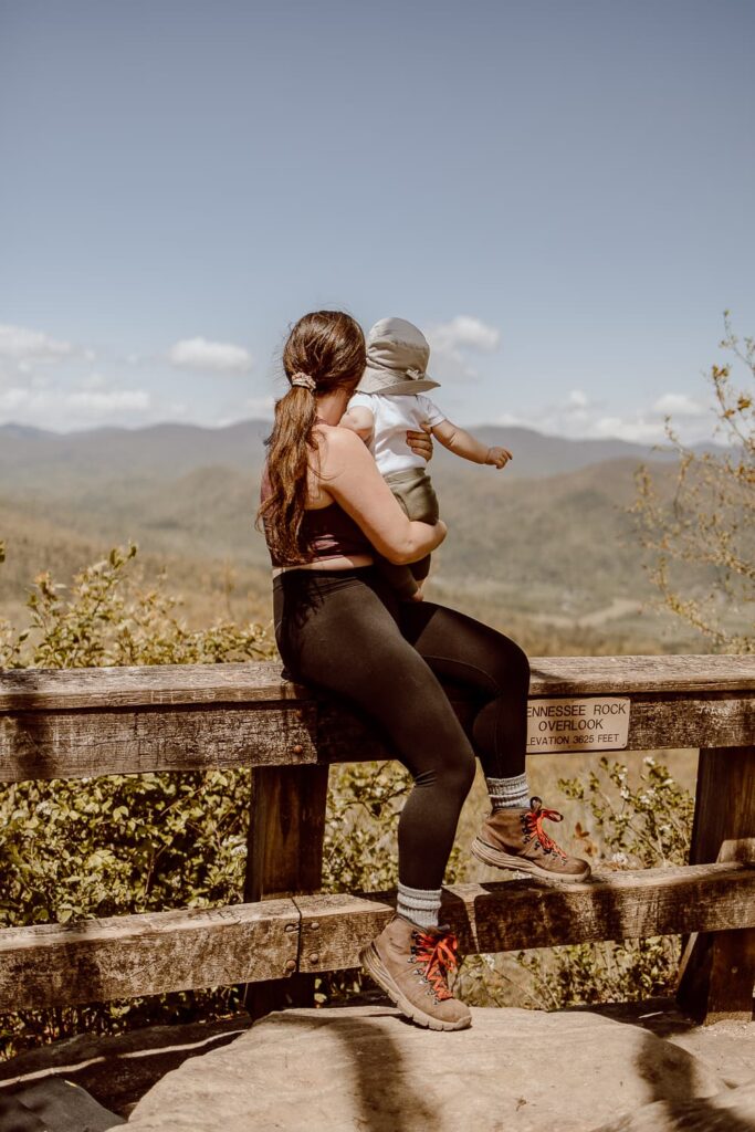 Woman and baby sitting on rail overlooking the mountains in Black Rock Mountain State Park.