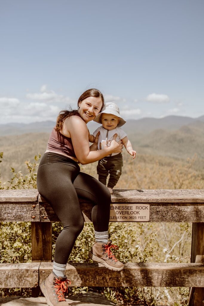 Woman sitting on rail with baby overlooking the mountains in Black Rock Mountain State Park in Georgia.