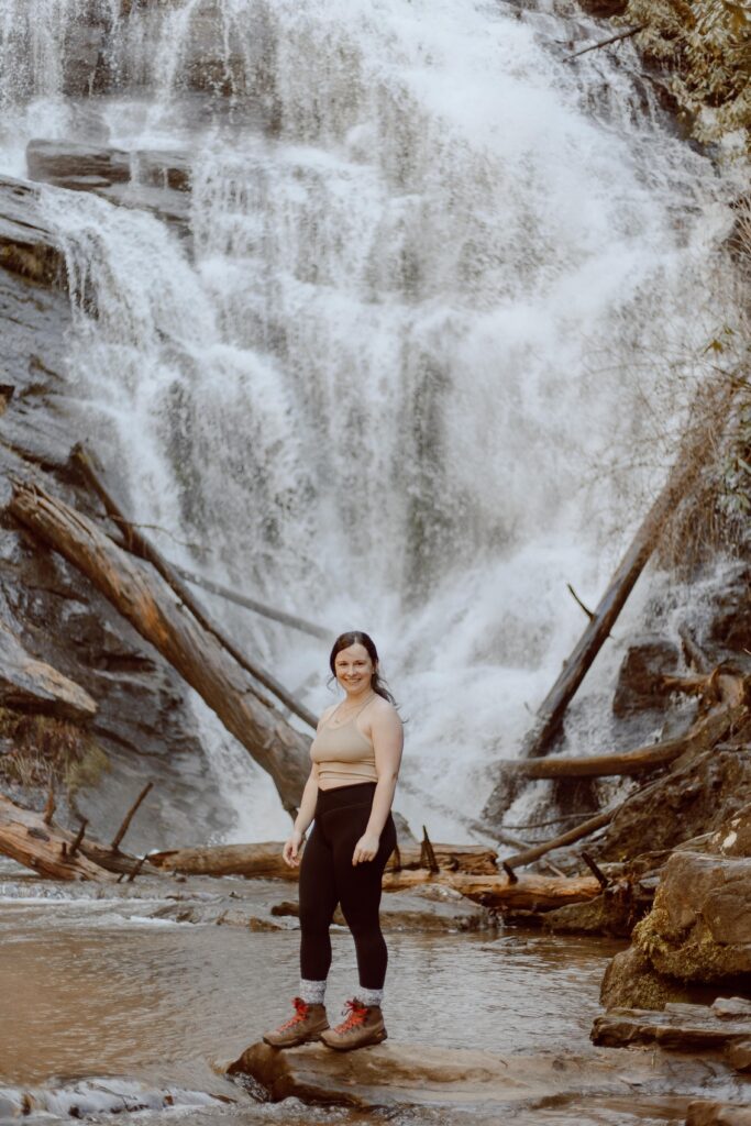 Woman standing on rock in front of King Creek Falls waterfall in South Carolina.