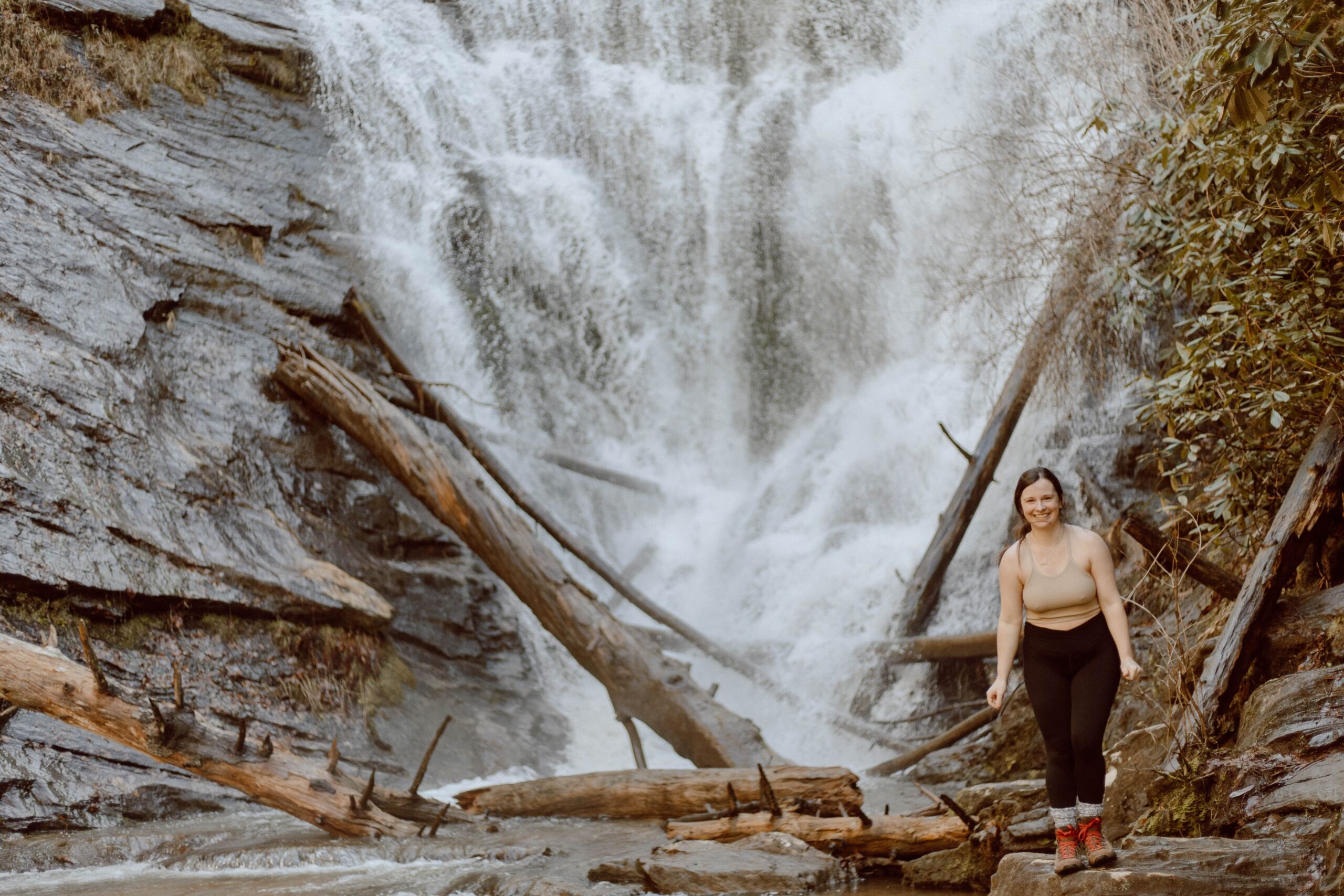 Woman standing on rock in front of King Creek Falls in South Carolina.