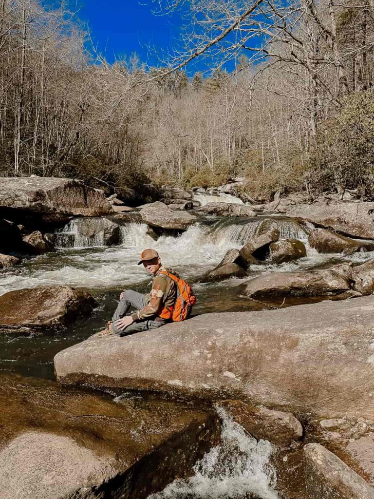 Boy sitting on rock in front of a river in North Carolina.
