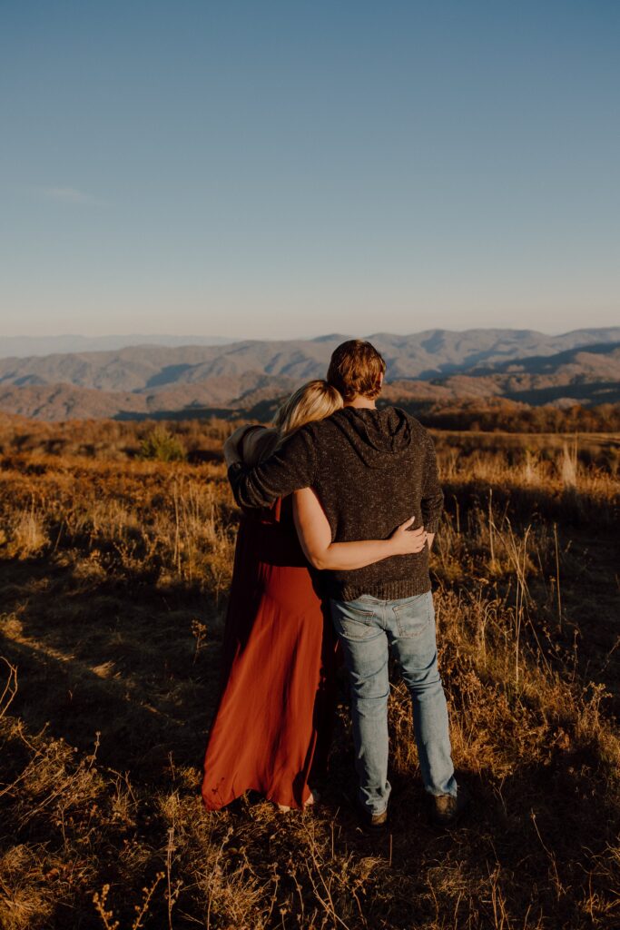 Man and woman hugging during sunset photoshoot at Max Patch Mountain in North Carolina.