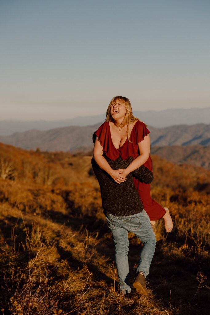 Man picking woman up during sunset photoshoot at Max Patch Mountain in North Carolina.