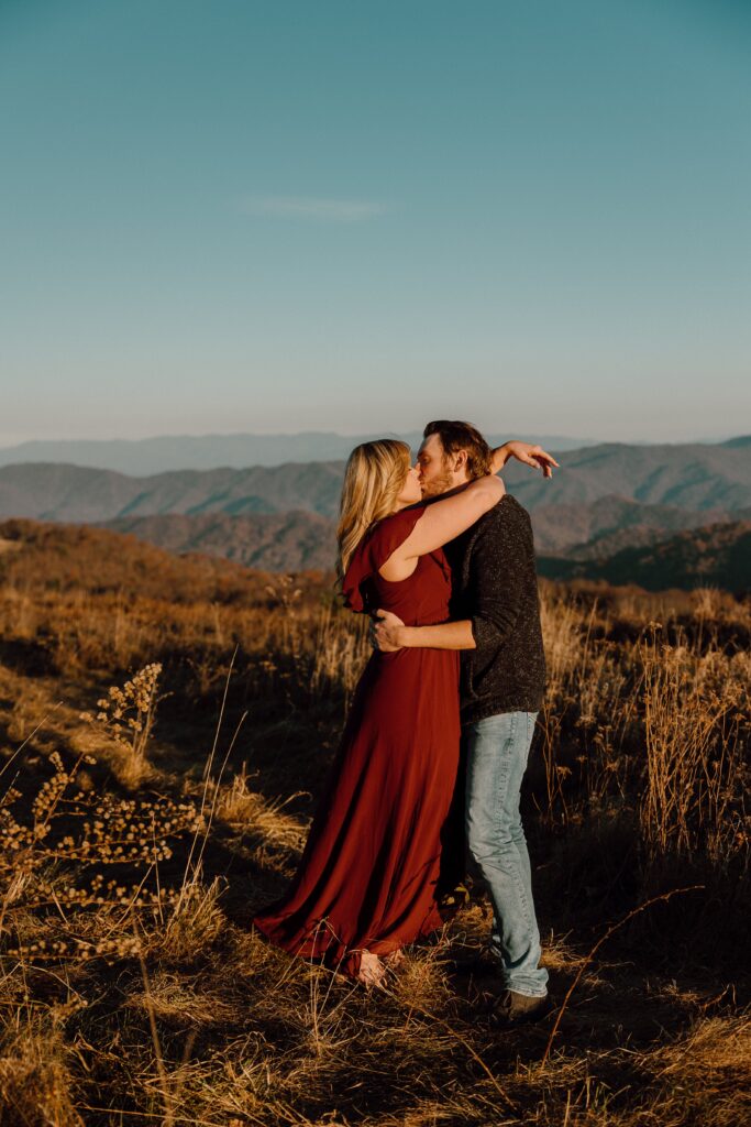 Man and woman kissing during sunset photoshoot at Max Patch Mountain in North Carolina.