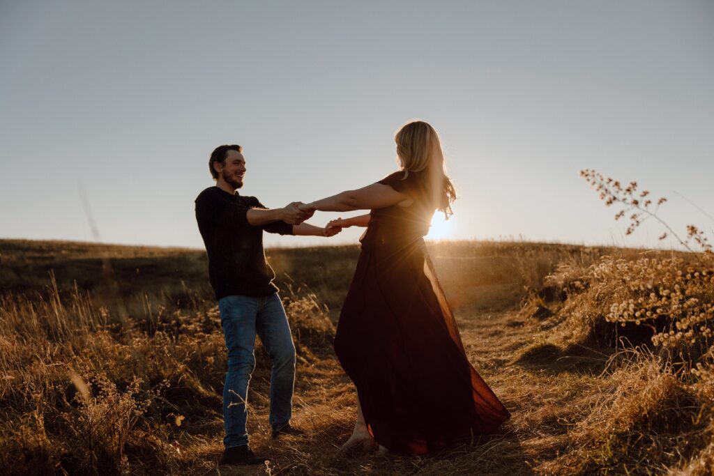 Man and woman holding hands and spinning during sunset photoshoot at Max Patch Mountain in North Carolina.