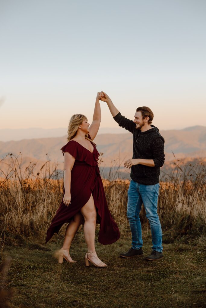 Man and woman holding hands and spinning during sunset photoshoot at Max Patch Mountain in North Carolina.