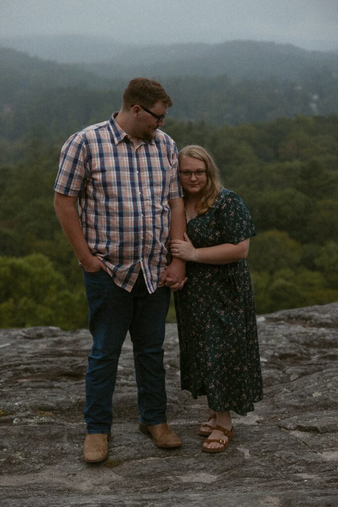 Man looking down at woman holding his arm during engagement photos.