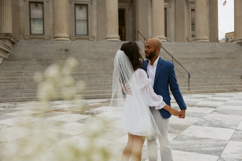 Man and woman hugging in wedding attire at courthouse in Charleston. 