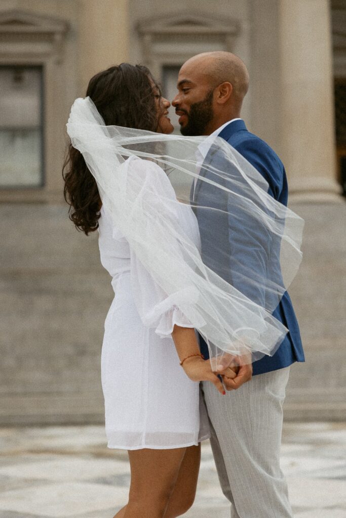 Man and woman about to kiss in wedding attire at courthouse in Charleston. 