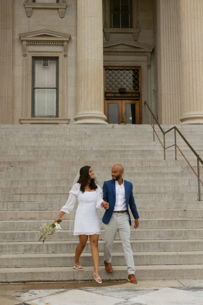 Man and woman holding hands and walking down courthouse steps in Charleston.