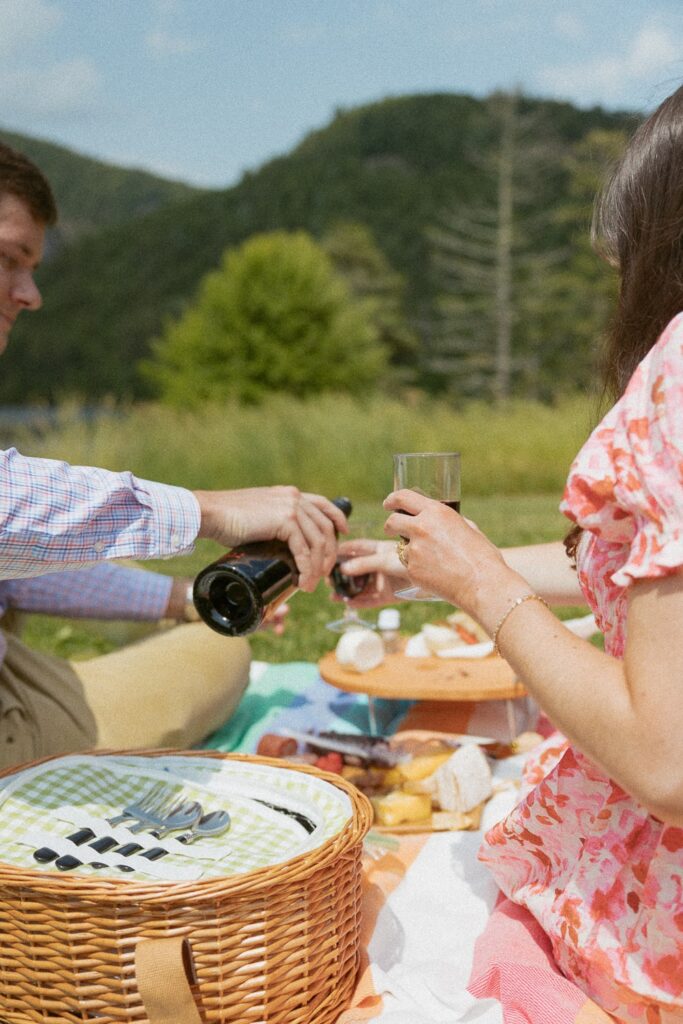 Man pouring a glass of wine for woman during a picnic.