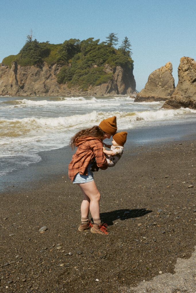 woman with baby playing on beach in washington. 