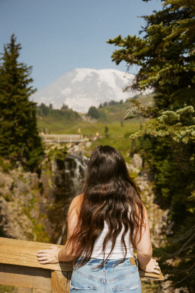 woman standing in front of myrtle falls with mt rainier in the background.