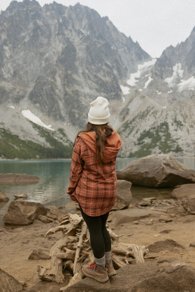 woman looking at alpine lake with snow cap mountains.