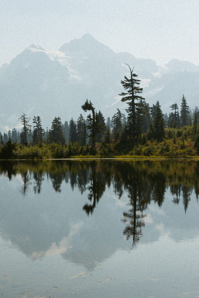 mountains and trees reflecting in lake.