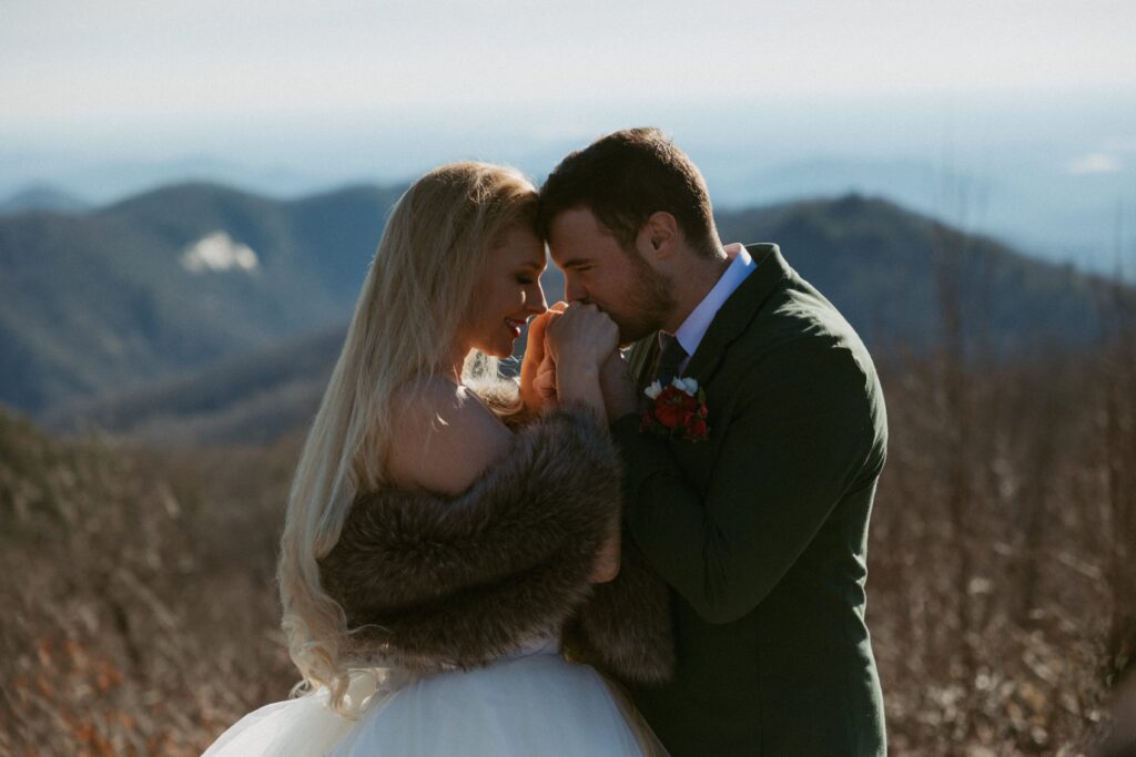 Man and woman touching foreheads and holding hands during elopement at Sassafras Mountain.