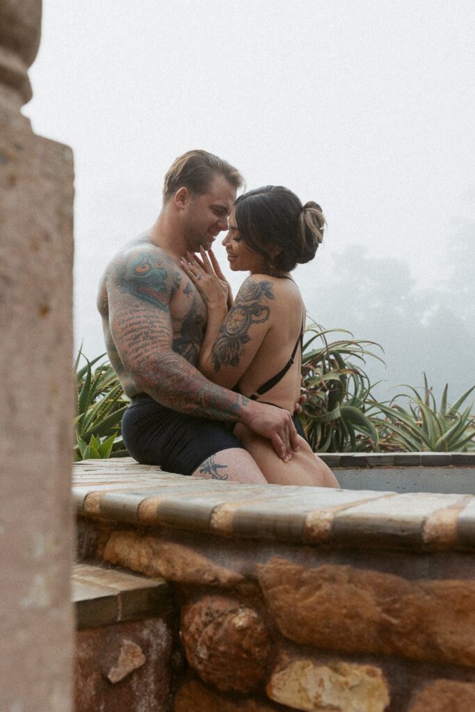 Man and woman laughing and hugging in a hot tub. 