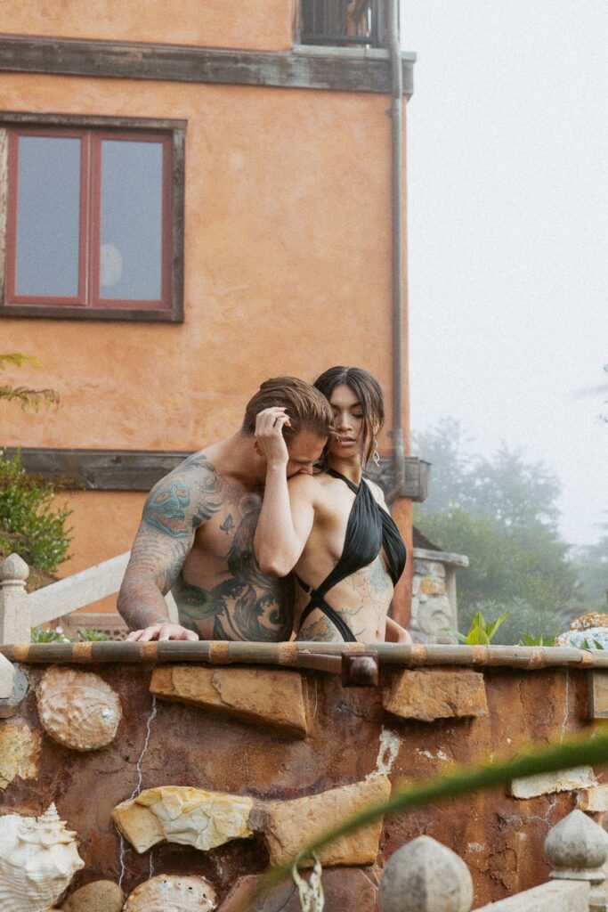 Man kissing woman's shoulder while in a hot tub. 