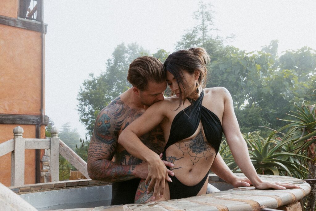 Man kissing woman's shoulder in a hot tub. 