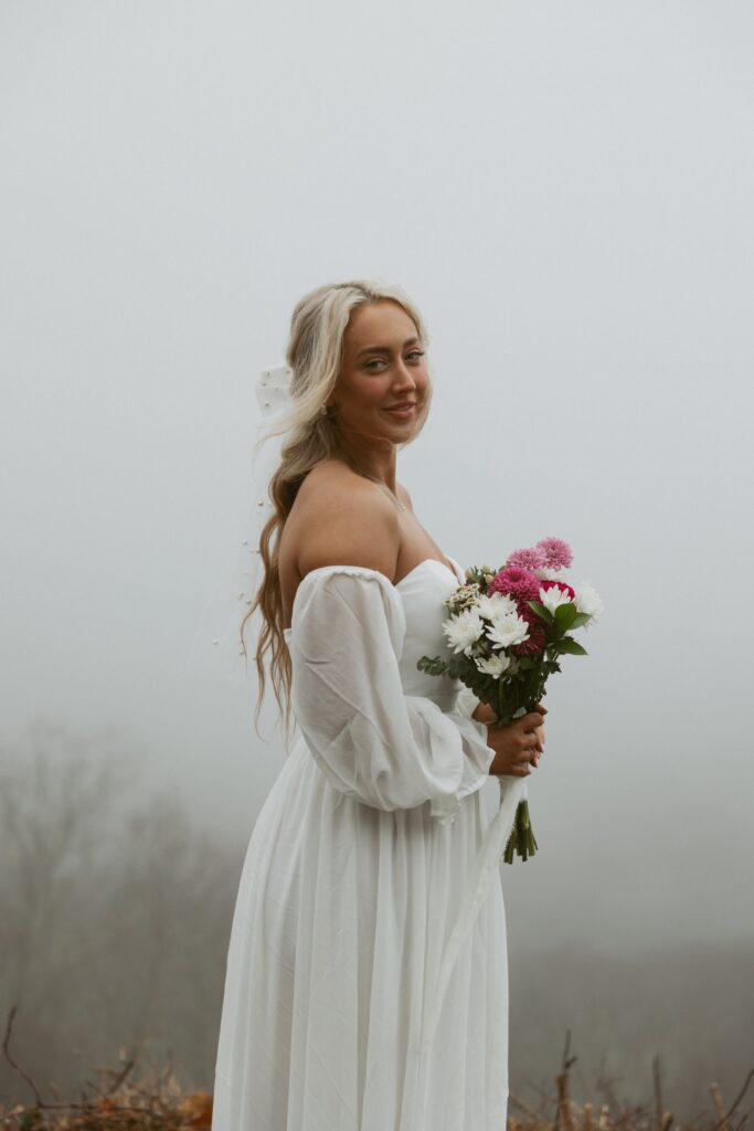 Woman wearing wedding dress and holding flowers.