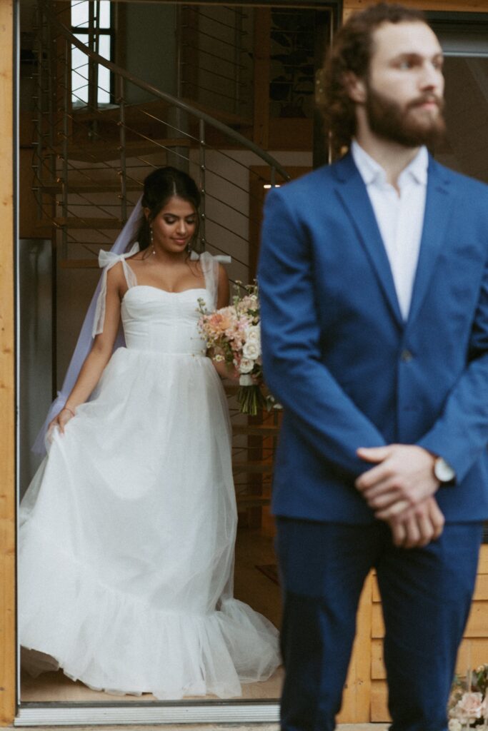 Woman in a wedding dress walking up behind a man in a suit. 