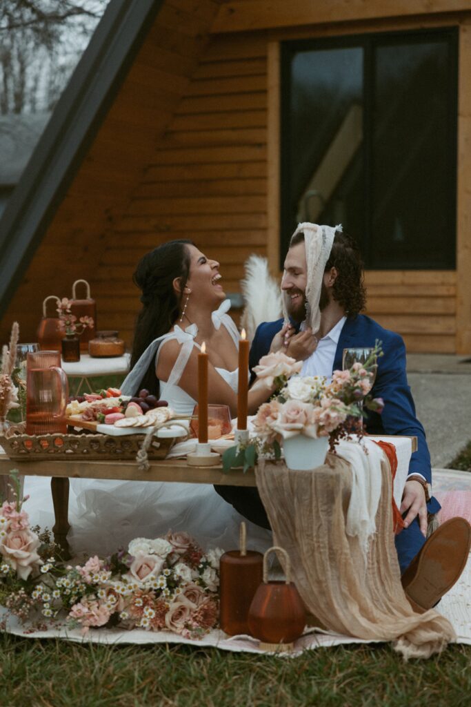 Man and woman laughing during picnic at wedding reception.