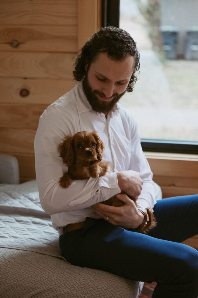 Man sitting on couch holding a small dog.