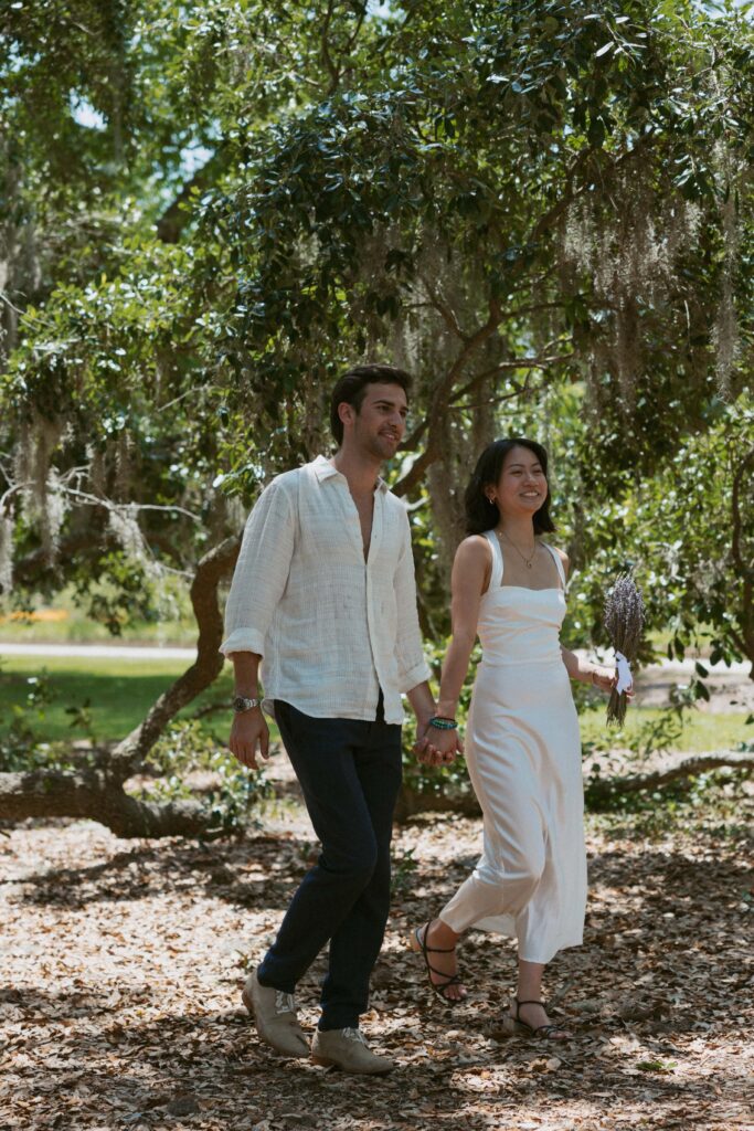 Man and woman walking underneath a spanish moss tree. 