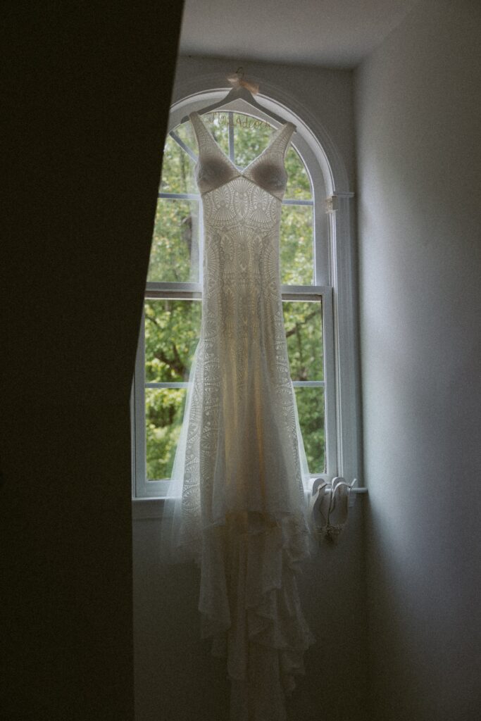 Wedding dress and wedding shoes hanging in window. 