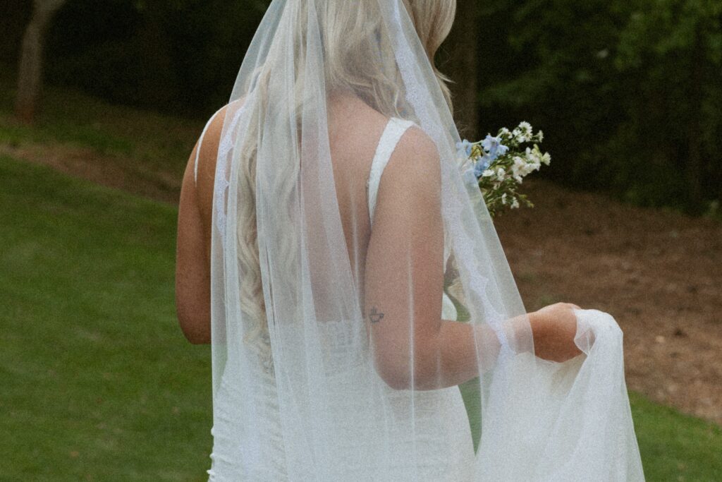 Woman in wedding dress holding her veil and flowers while walking. 