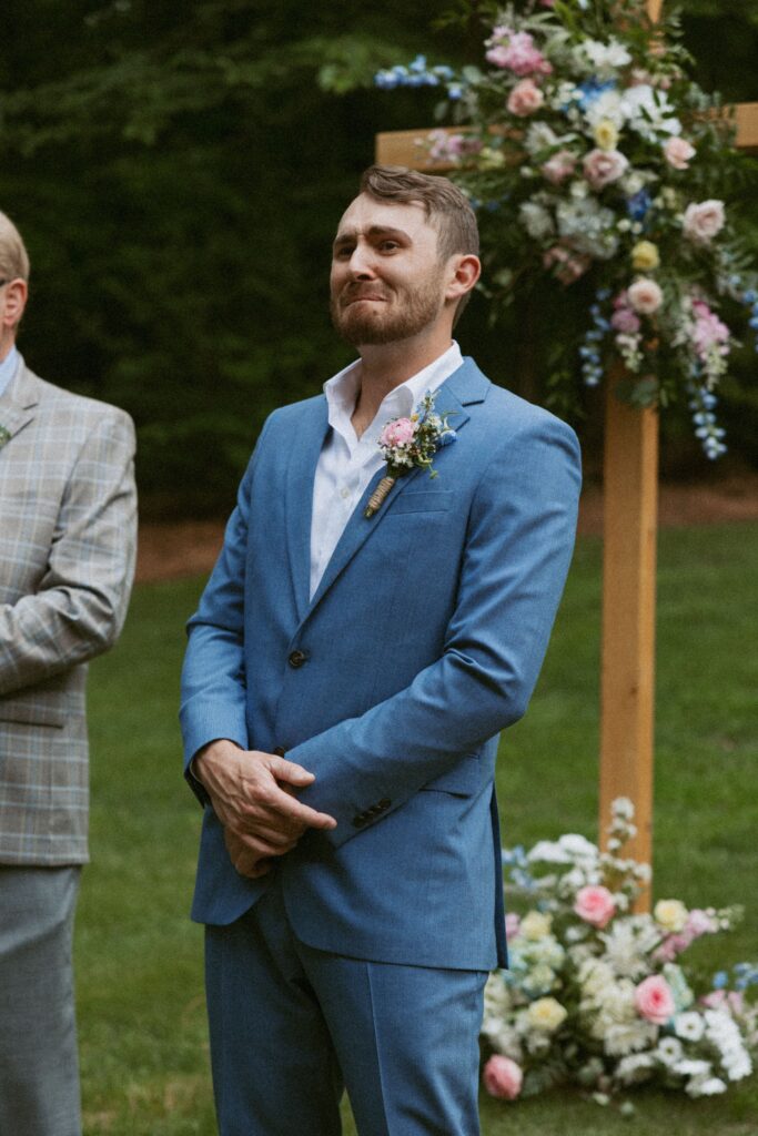 Man in blue suit standing at alter crying. 