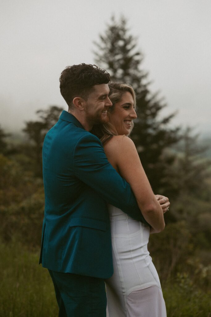 Man hugging woman from behind while they laugh.