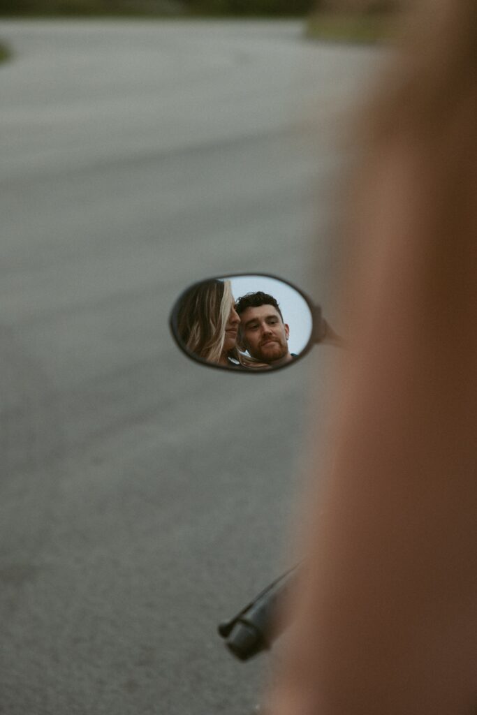 Man and woman in a motorcycle side mirror.