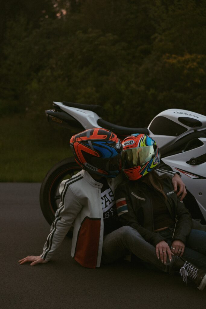 Man and woman in helmets sitting in front of motorcycle.