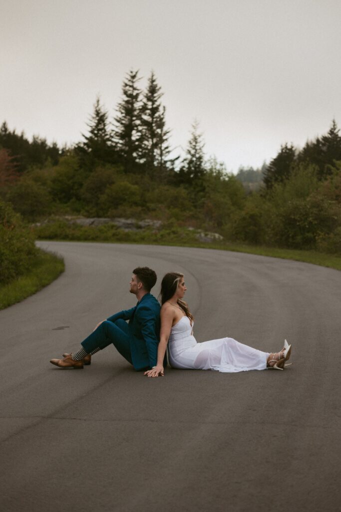 Man and woman sitting in road back to back.