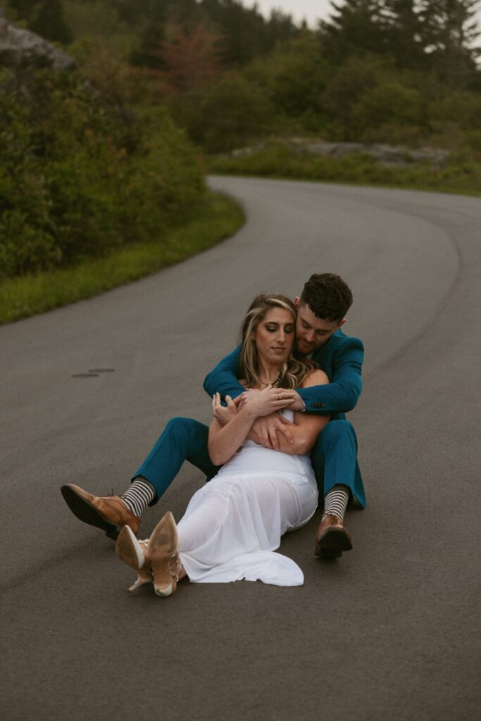 Woman sitting between mans legs in the road.