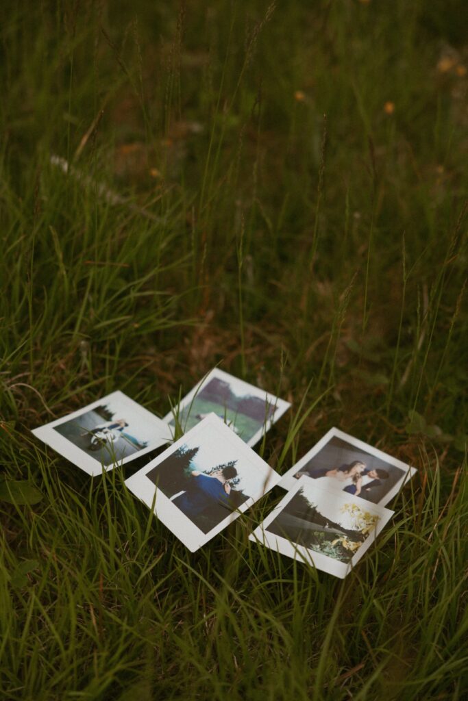 5 polaroid pictures laying in the grass.