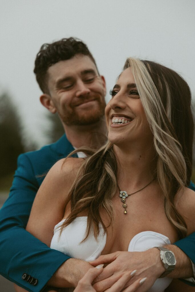 Man hugging woman from behind while they laugh.