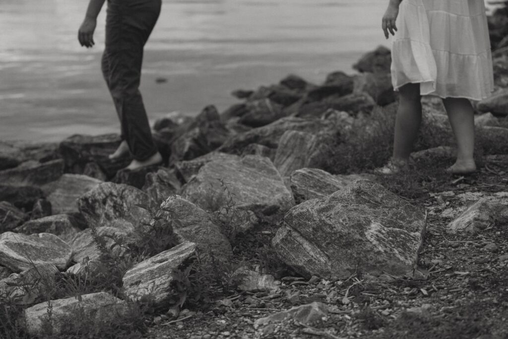 Man and woman walking barefoot over rocks. 