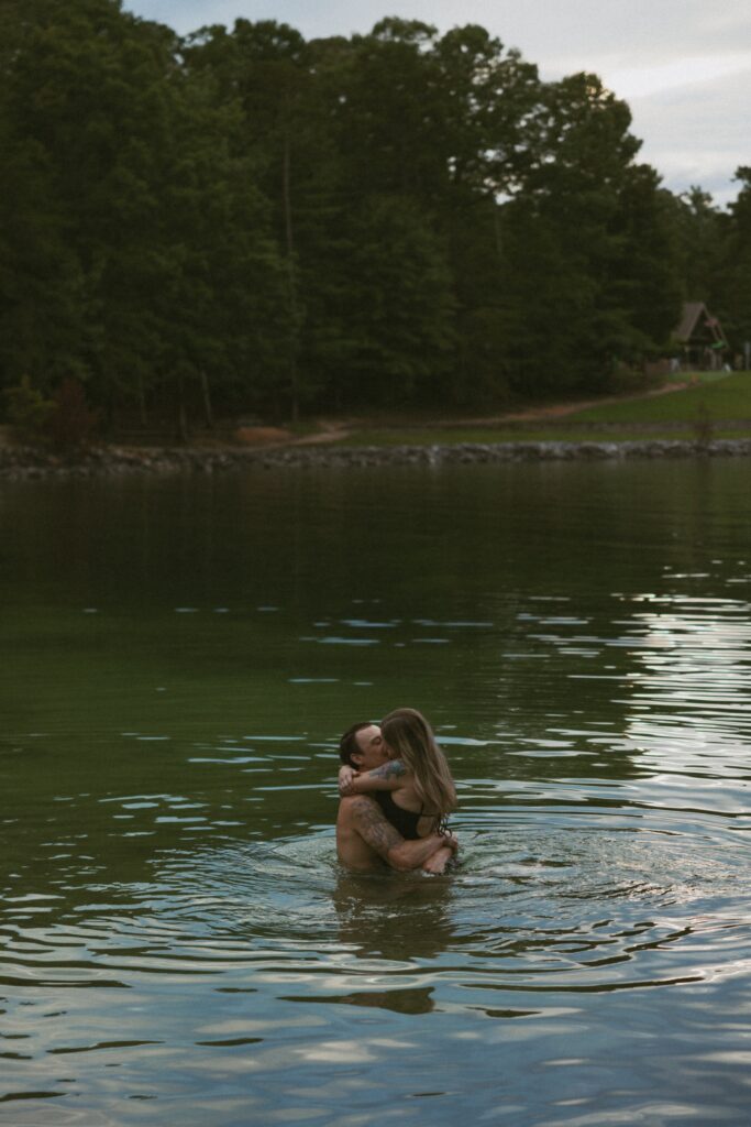 Man holding a woman in the water and kissing. 