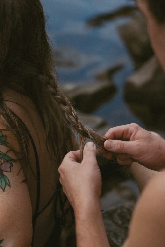 Close up of a man braiding a womans hair. 