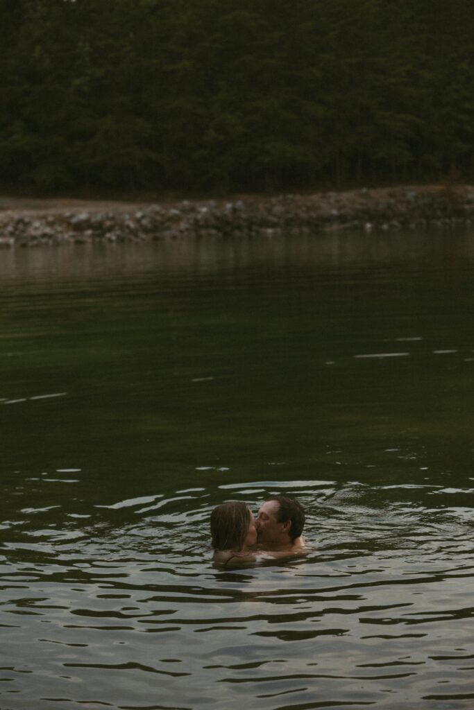 Man and woman neck deep in the water while kissing. 