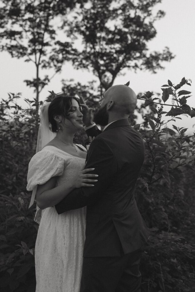 Man and woman in wedding attire hugging while facing each other. 