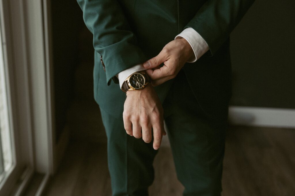 Close up of a man fixing his tux sleeve on his wedding day with his watch showing. 