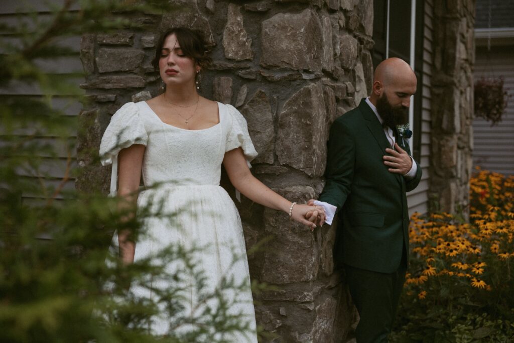 Man and woman holding hands around a corner of a building on their wedding day.