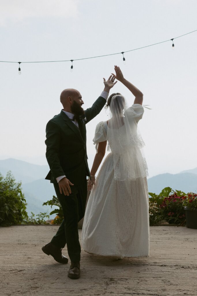 Man and woman dancing during their first dance on their wedding day in front of mountains.