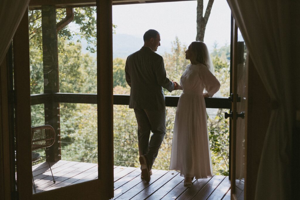 Man and woman standing on deck of Airbnb in wedding attire.